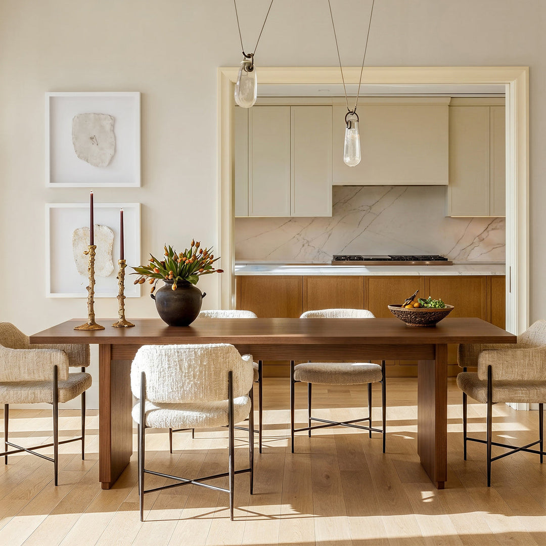 Walnut-tone rectangular wood dining table with boucle chairs and glass pendants in a modern dining room