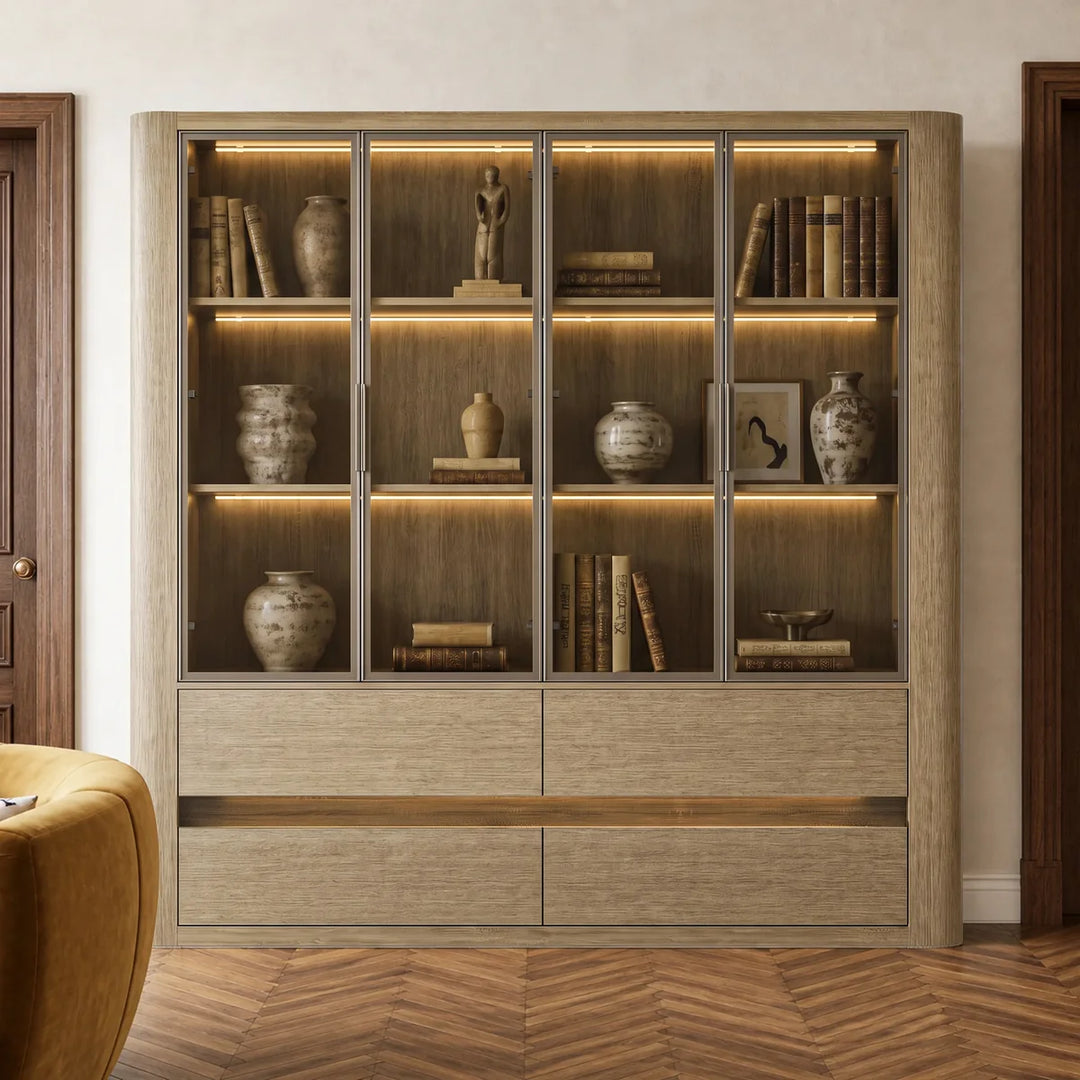 Wide oak display cabinet with lit glass doors full of books and ceramics