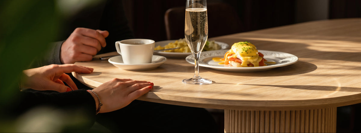 Person sitting at a table with a plate of food and a glass of champagne.