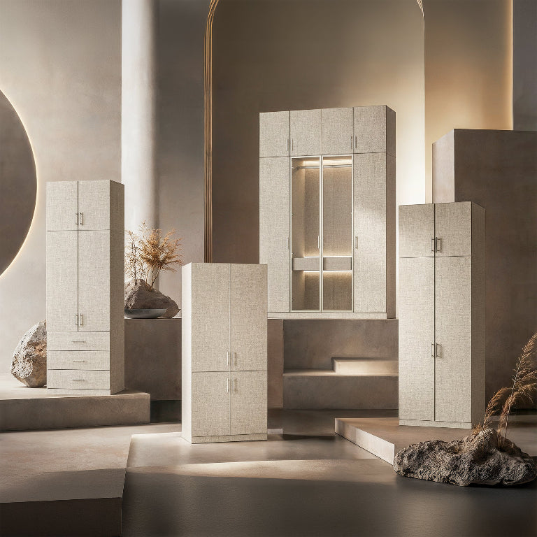 A set of modern linen-textured storage cabinets in warm beige and off-white tones, arranged on minimalist concrete platforms with warm architectural lighting and decorative rocks.